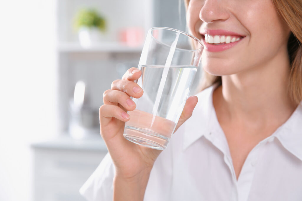 A woman holds a full glass of clear drinking water